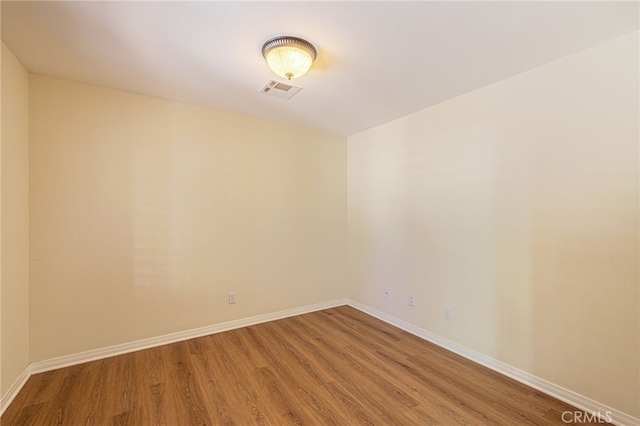 spare room featuring light wood-type flooring, visible vents, and baseboards