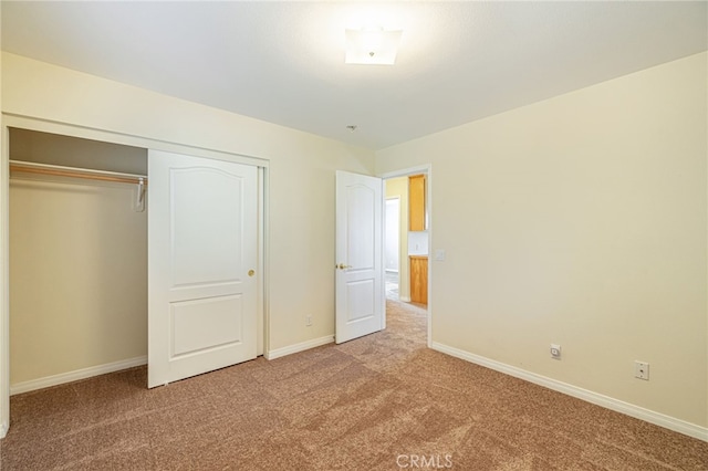 unfurnished bedroom with a closet, baseboards, and carpet flooring