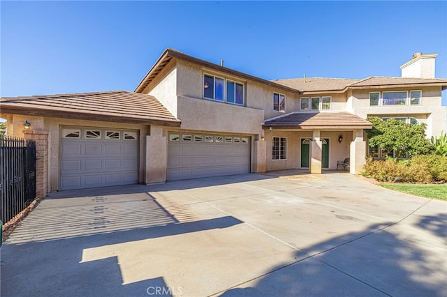 view of front of home featuring driveway, a tile roof, fence, and stucco siding