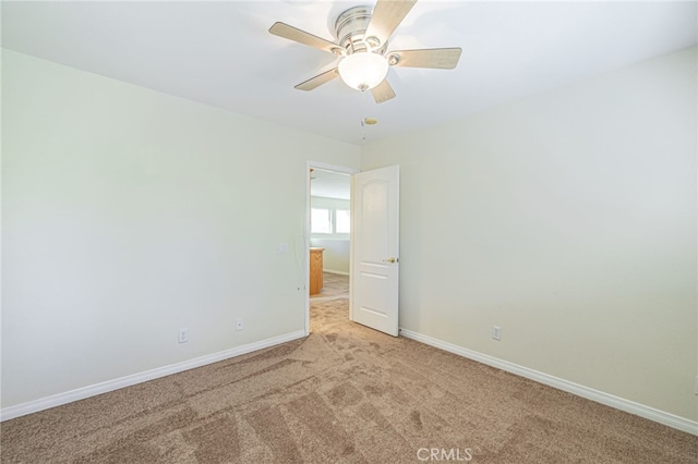 spare room with light carpet, ceiling fan, and baseboards