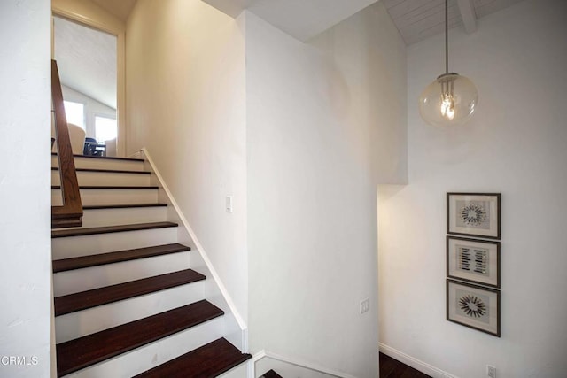 staircase featuring baseboards and vaulted ceiling