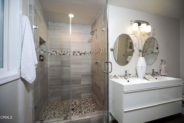 bathroom featuring a stall shower, a sink, and double vanity