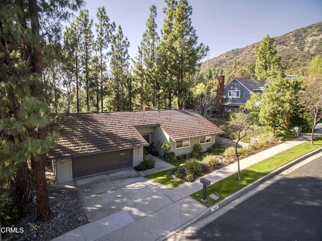 view of front facade with a mountain view, driveway, an attached garage, and stucco siding