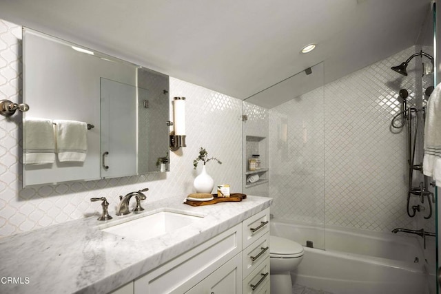 bathroom with bathtub / shower combination, toilet, vanity, tile walls, and tasteful backsplash