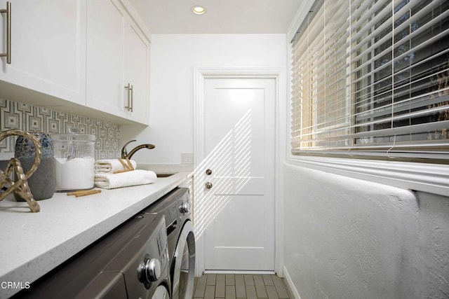 clothes washing area with washer and clothes dryer, recessed lighting, cabinet space, a sink, and baseboards