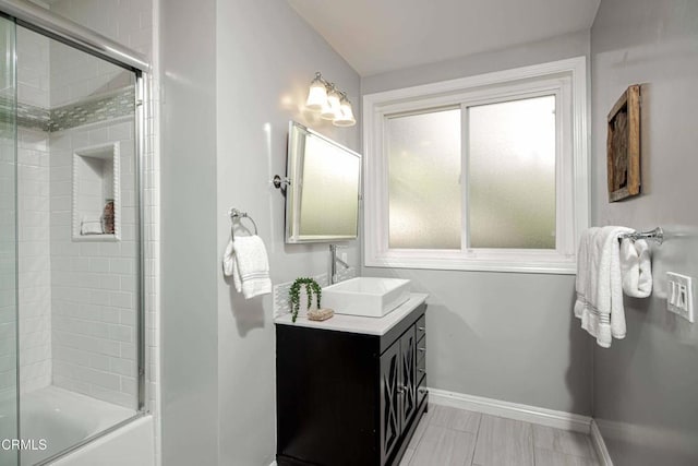 bathroom featuring shower / bath combination with glass door, vanity, and baseboards