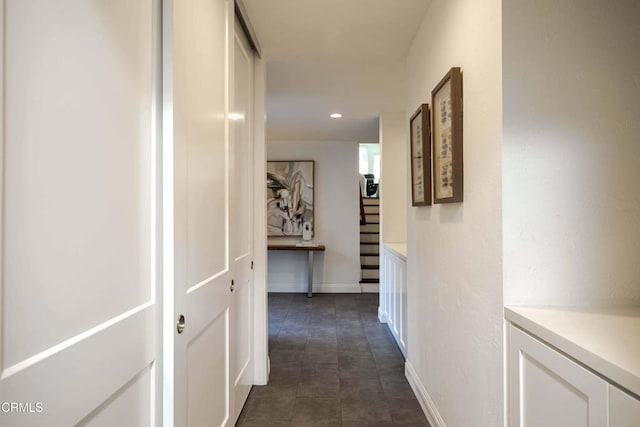 hallway with recessed lighting, dark tile patterned flooring, baseboards, and stairs