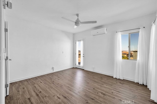 unfurnished room with ceiling fan, baseboards, wood finished floors, and a wall mounted air conditioner