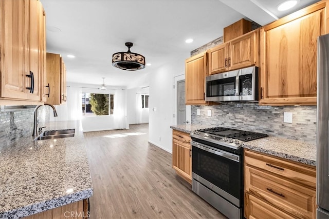 kitchen with light stone countertops, tasteful backsplash, stainless steel appliances, and a sink