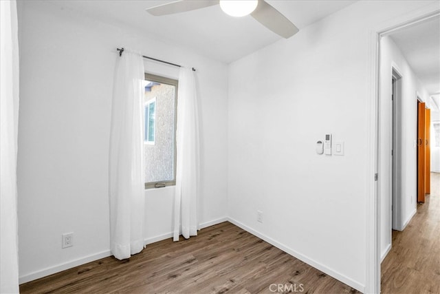 unfurnished room featuring ceiling fan, baseboards, and wood finished floors