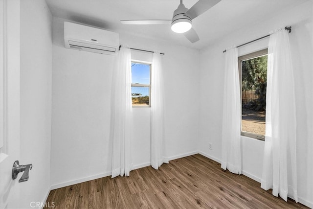 spare room with plenty of natural light, ceiling fan, wood finished floors, and a wall mounted AC