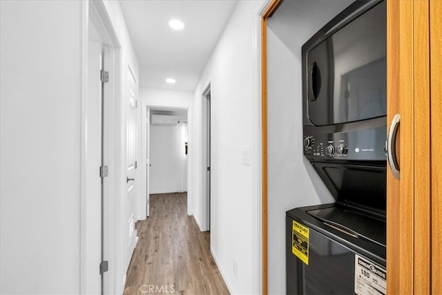 corridor featuring stacked washer and dryer, an AC wall unit, wood finished floors, and recessed lighting