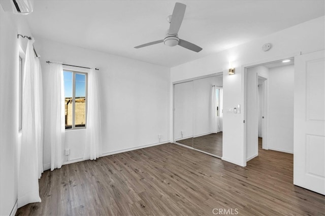 unfurnished bedroom featuring baseboards, a closet, a ceiling fan, and wood finished floors