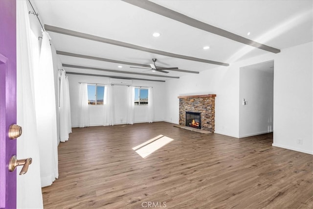 unfurnished living room with a ceiling fan, wood finished floors, beamed ceiling, a fireplace, and recessed lighting