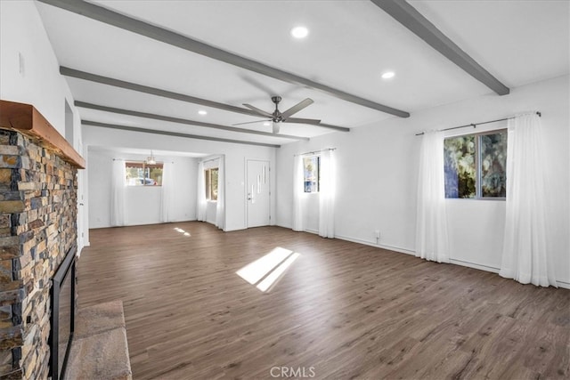 unfurnished living room with a healthy amount of sunlight, a fireplace, wood finished floors, and beamed ceiling