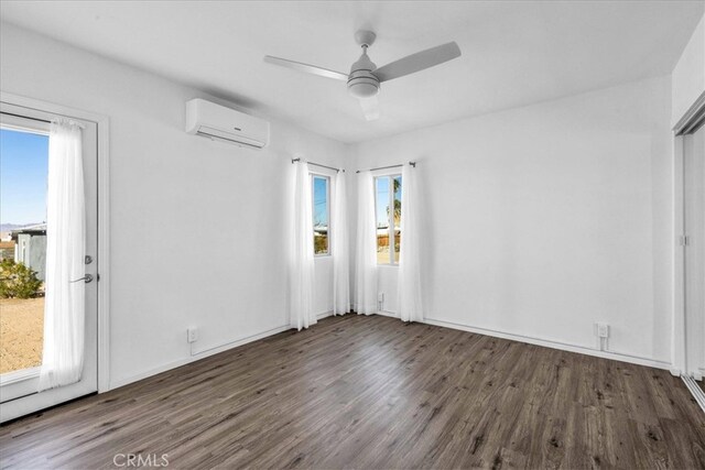 empty room featuring baseboards, a ceiling fan, wood finished floors, and a wall mounted air conditioner