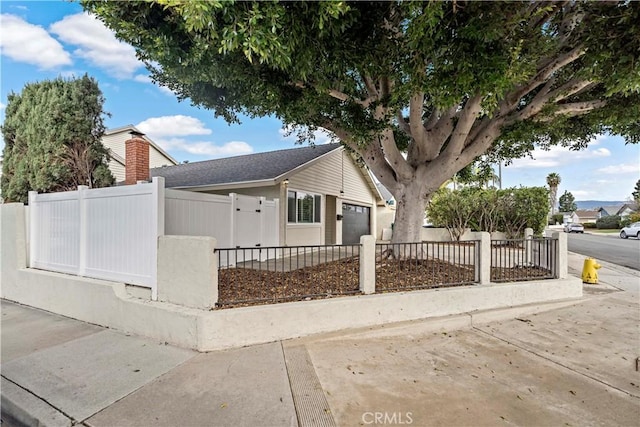 view of front of house featuring a garage, driveway, and a fenced front yard