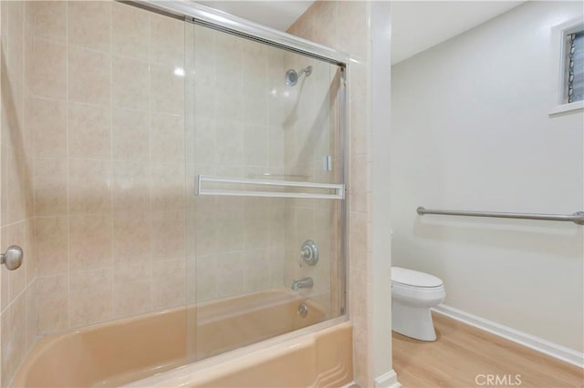 bathroom featuring enclosed tub / shower combo, wood finished floors, toilet, and baseboards