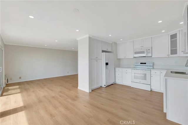 kitchen with white appliances, open floor plan, light countertops, ornamental molding, and light wood-type flooring