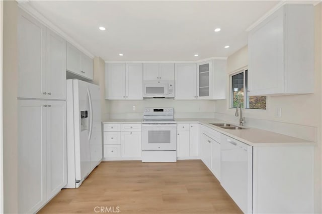 kitchen featuring recessed lighting, white appliances, a sink, light countertops, and light wood finished floors