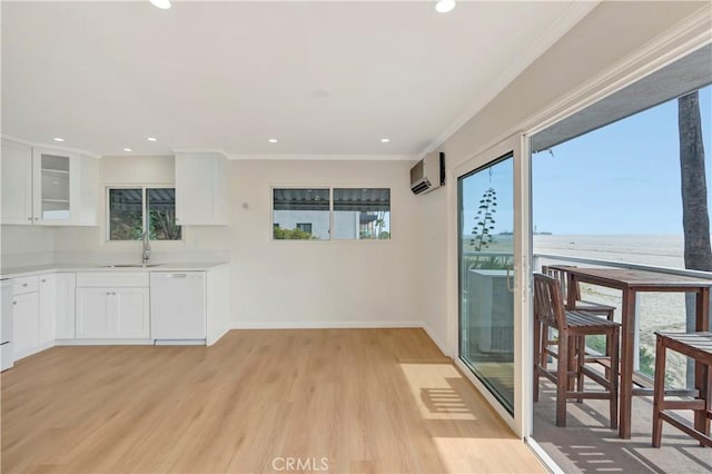 interior space featuring light wood finished floors, white dishwasher, white cabinetry, and a wall mounted air conditioner