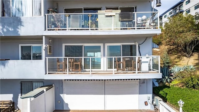 back of house featuring a balcony and stucco siding