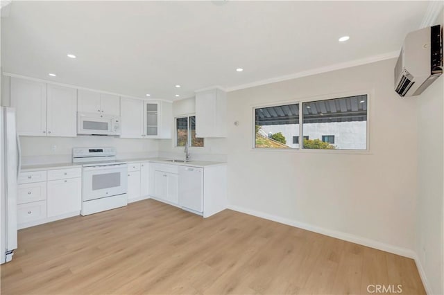 kitchen featuring white appliances, a wall mounted AC, a sink, and light wood-style flooring