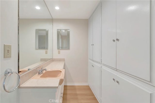 bathroom featuring recessed lighting, baseboards, wood finished floors, and vanity