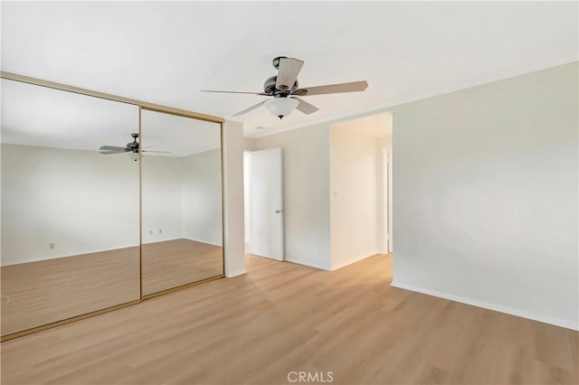 unfurnished bedroom with light wood-style floors, baseboards, a ceiling fan, and a closet