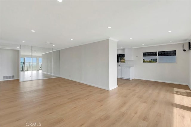 empty room featuring light wood finished floors, baseboards, visible vents, crown molding, and recessed lighting