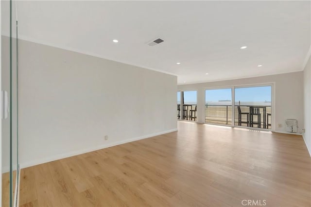 empty room featuring light wood-style flooring, baseboards, crown molding, and recessed lighting