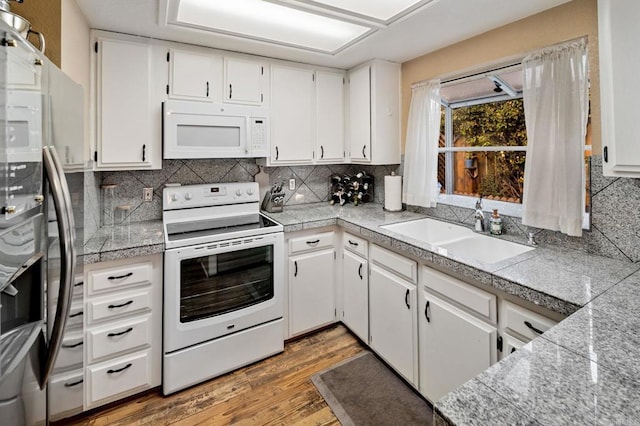 kitchen with tile counters, tasteful backsplash, a sink, wood finished floors, and white appliances