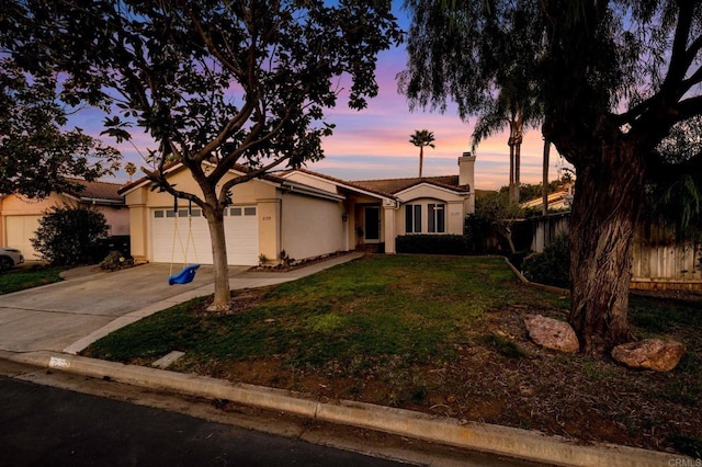 single story home with a garage, a tile roof, concrete driveway, a yard, and stucco siding