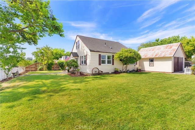 rear view of property with an outbuilding, a fenced backyard, and a yard