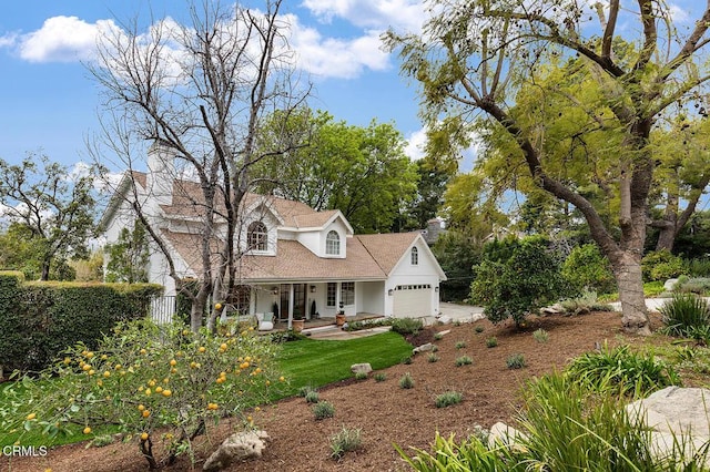 view of front of home with an attached garage, covered porch, and a chimney