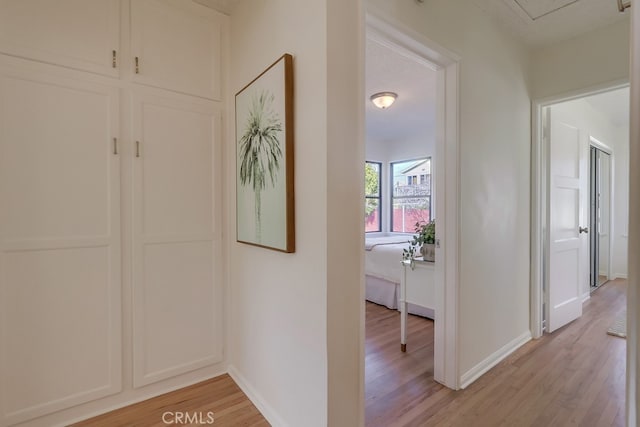 corridor featuring light wood-style flooring and baseboards