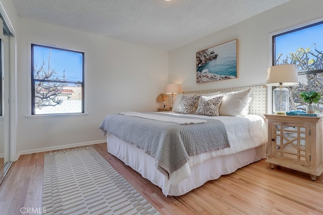 bedroom featuring a textured ceiling, baseboards, and wood finished floors