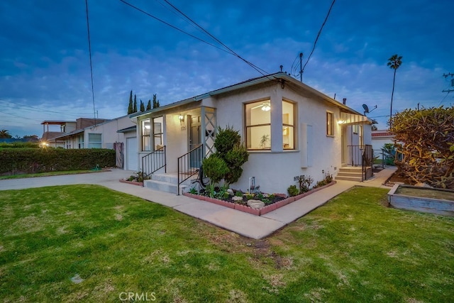 bungalow with a garage, a front yard, concrete driveway, and stucco siding