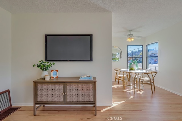 interior space featuring ceiling fan, a textured ceiling, baseboards, and wood finished floors