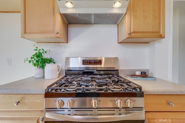 kitchen featuring light countertops, light brown cabinetry, stainless steel range with gas stovetop, and exhaust hood