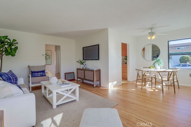 living area featuring light wood-type flooring, baseboards, visible vents, and a ceiling fan