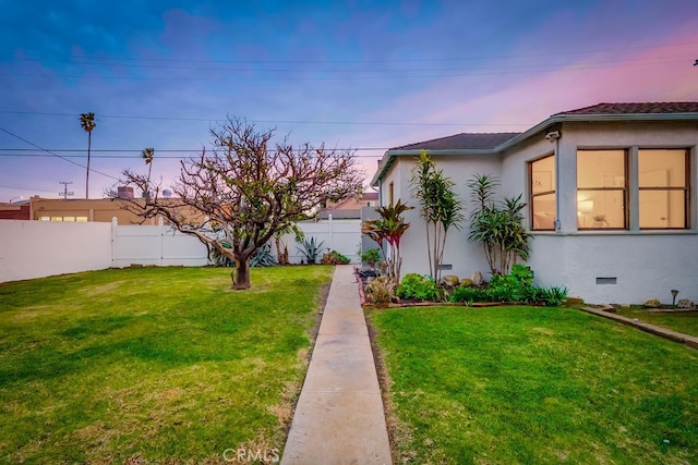 yard at dusk featuring a fenced backyard