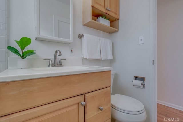 bathroom featuring baseboards, vanity, toilet, and wood finished floors