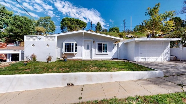 view of front facade with a garage, a front yard, concrete driveway, and stucco siding