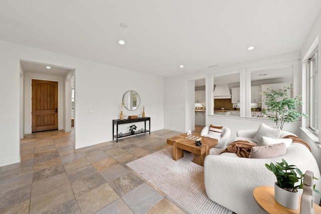 living area featuring baseboards, stone tile flooring, and recessed lighting