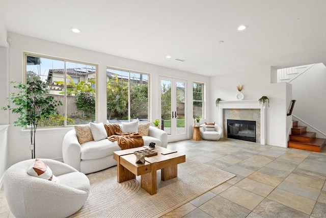 living area with french doors, stairway, plenty of natural light, and a fireplace