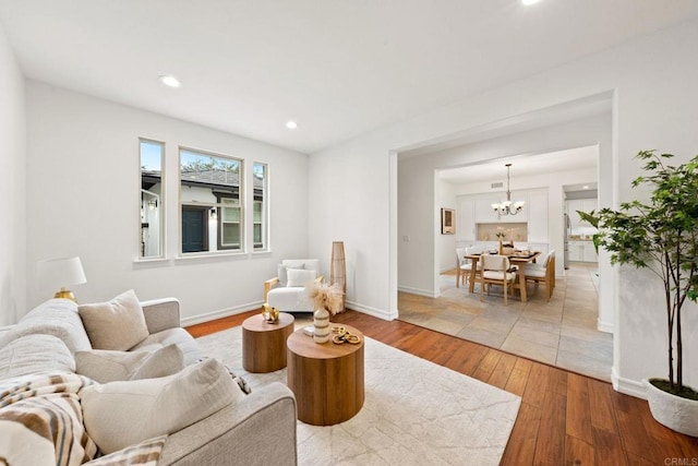 living area featuring a chandelier, recessed lighting, baseboards, and hardwood / wood-style floors