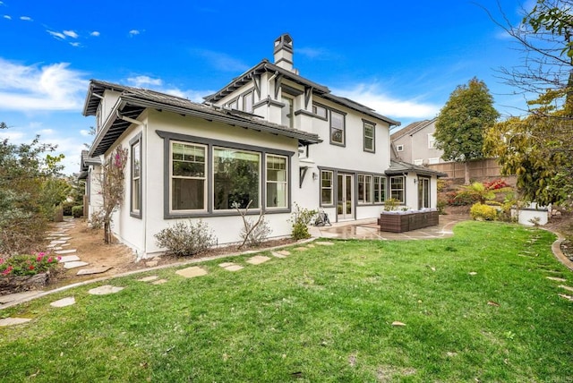 rear view of property with a patio, fence, a lawn, stucco siding, and a chimney