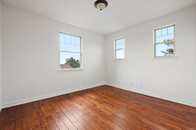 empty room with baseboards and hardwood / wood-style flooring