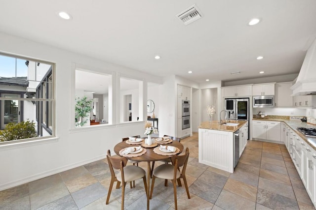 kitchen with a center island with sink, recessed lighting, visible vents, appliances with stainless steel finishes, and a sink